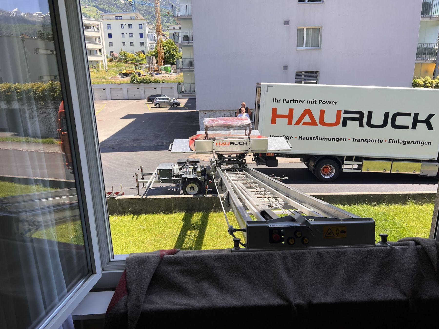 Umzugslift durch ein Fenster ausgefahren, HAURUCK-Lastwagen im Hintergrund